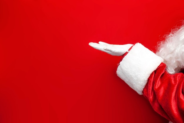 empty hand of santa claus in suit and gloves holding empty space on red background