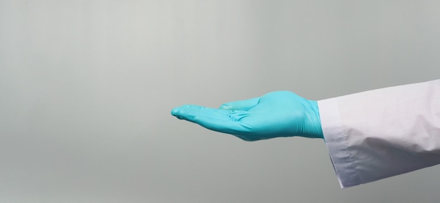 Photo empty hand wear doctor gown and blue medical glove on grey background. studio shooting.