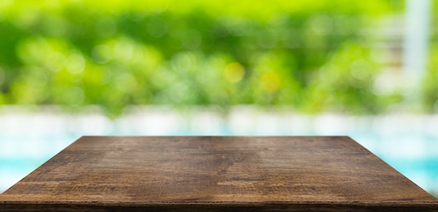 Empty hard wood table and blurred hedge and pool