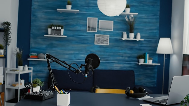 Empty home studio desk with professional audio equipment on table. Podcast broadcast desk having recording devices and gadgets inside living room with nobody in it. Studio shot