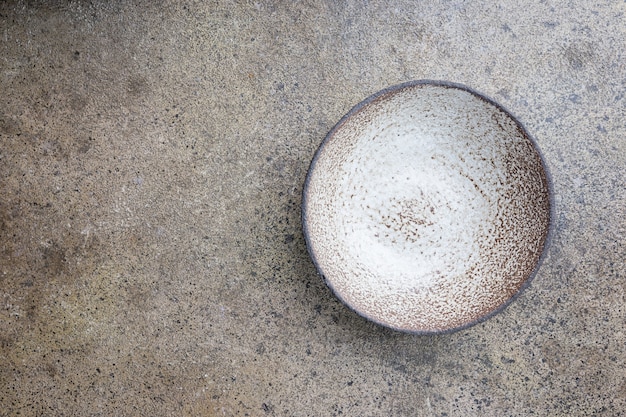 Empty homemade ceramic bowl on grey stone background, top view