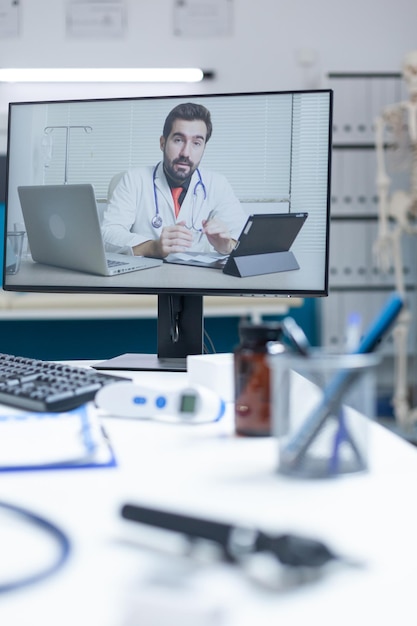 Empty hospital office with remote doctor having online medical discussion during telemedicine videocall meeting conference. Computer with telework videoconference call on screen. Medicine support