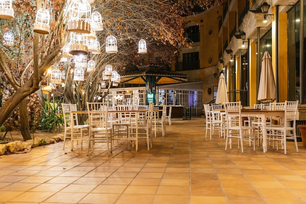 Empty hotel terrace at night with illuminated lanterns in the trees