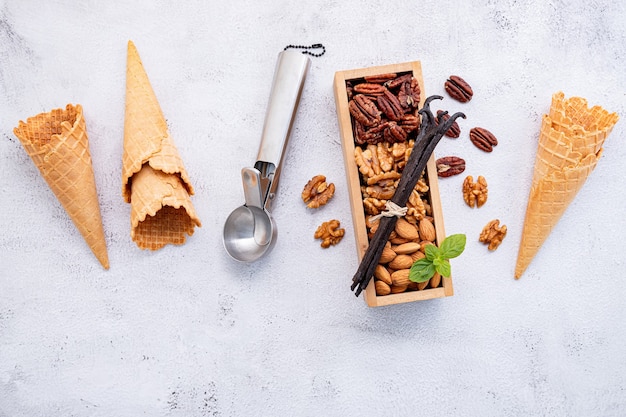 Empty  ice cream cones with mixed nut setup on white stone .