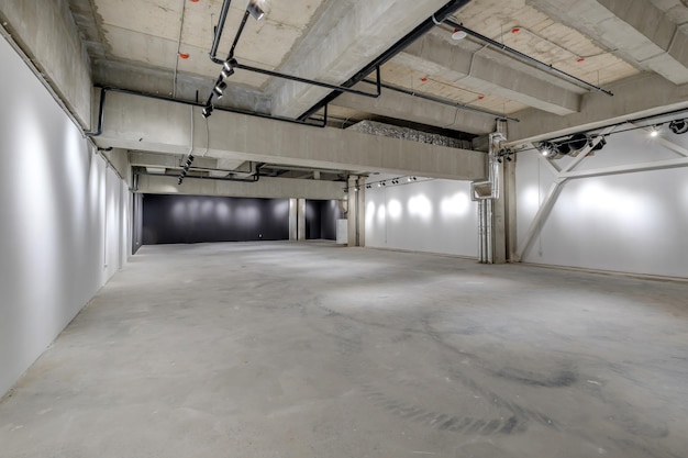 Empty interior of large concrete room as warehouse or hangar\
with spotlights