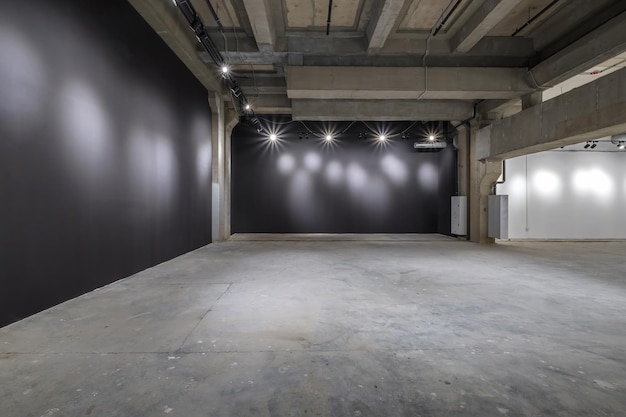 Empty interior of large concrete room as warehouse or hangar\
with spotlights