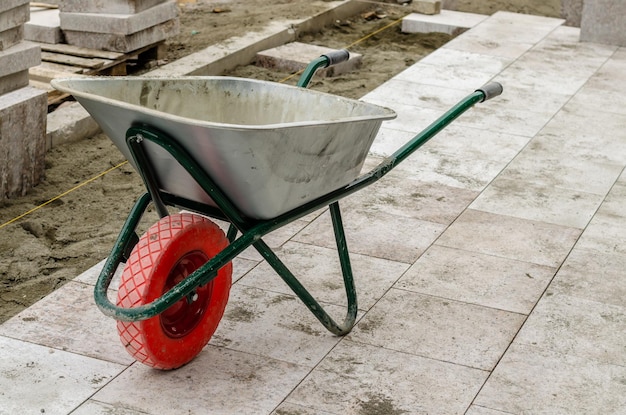 An empty iron wheelbarrow on the sidewalk repair.