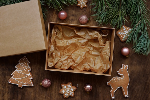 Foto scatola kraft vuota con coperchio marrone per dolci, biscotti sulla tavola di capodanno con pan di zenzero per la consegna a domicilio dalla pasticceria. concetto di consegna del cibo di capodanno.