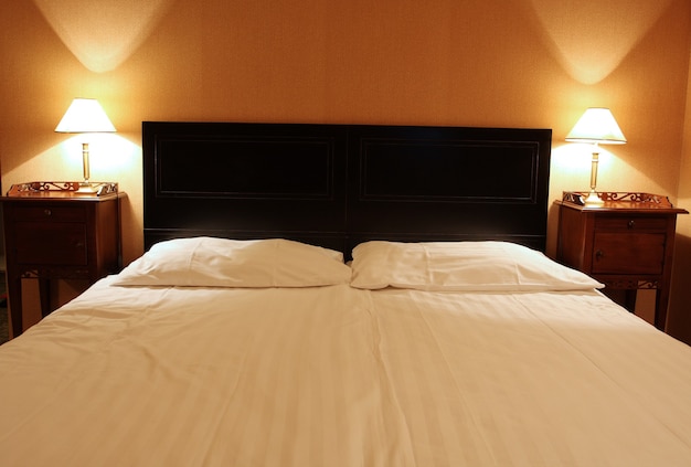 Empty large bed for two with the lamps at the heads