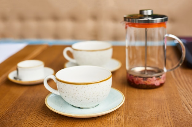 Empty leftover tea cups and teapot on wooden table in cafe or in kitchen at home