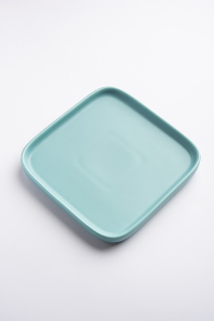 Пустая светло-зеленая или синяя керамическая квадратная тарелка, изолированная на белой поверхности
