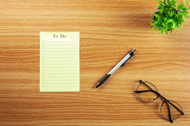 Empty to do list and a pen on wooden desk.