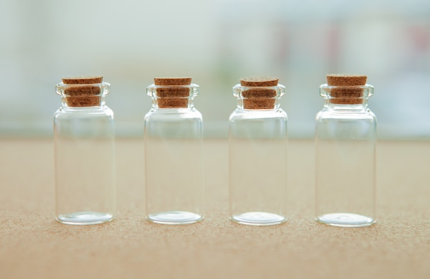 Empty little bottles with cork stopper, on blurred background