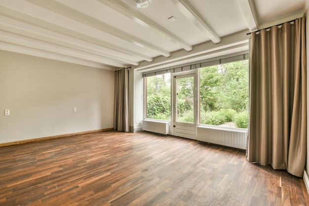 An empty living room with wood flooring and large windows in the room is very clean ready to use