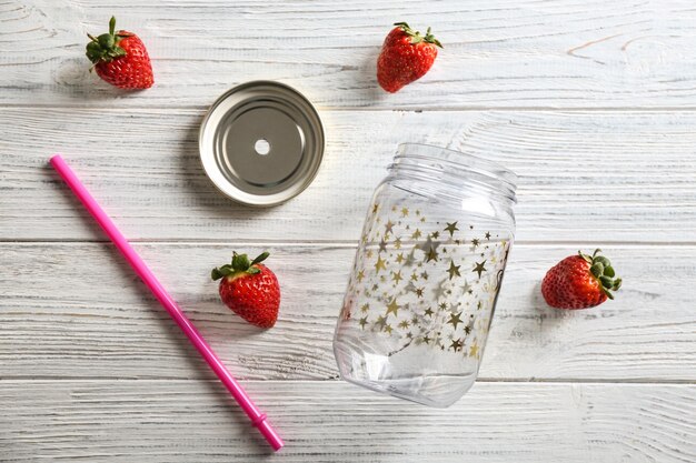 Empty mason jar with strawberries on wooden background