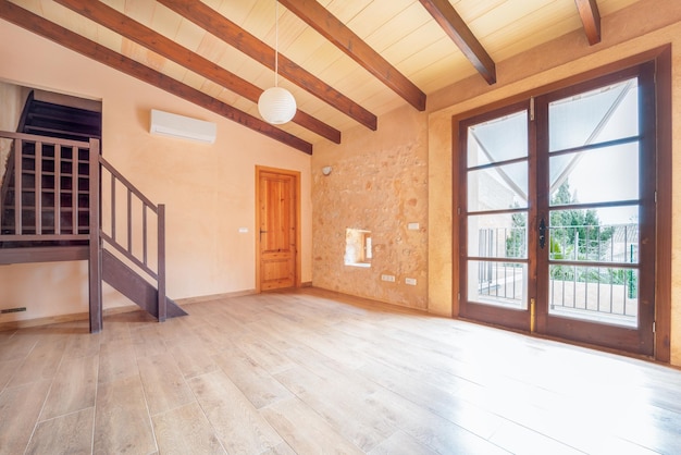 寄木細工の床の木製の梁のバルコニーと素朴なスタイルのエアコンを備えた空の主寝室