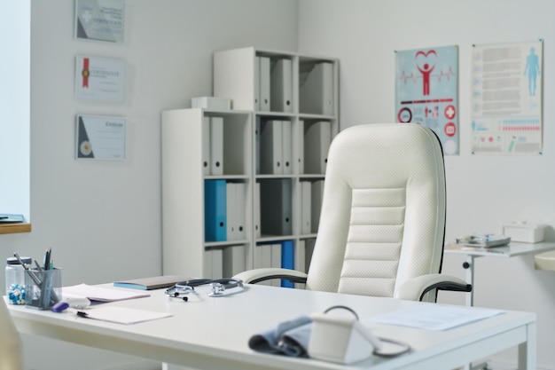 Photo empty medical office with workplace of clinician consisting of desk and armchair