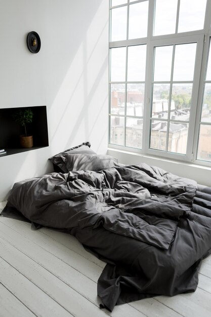 写真 現代的なインテリアの枕付きの空っぽの混沌とした濃い灰色のベッド