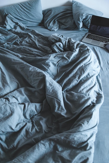 Empty messy grey bed with laptop. lifestyle rest in bed concept