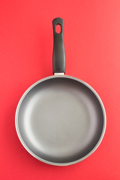 Empty metal frying pan on the red background. Location vertical.