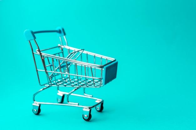 Empty metal shopping trolley on green , Discount and shopping concept