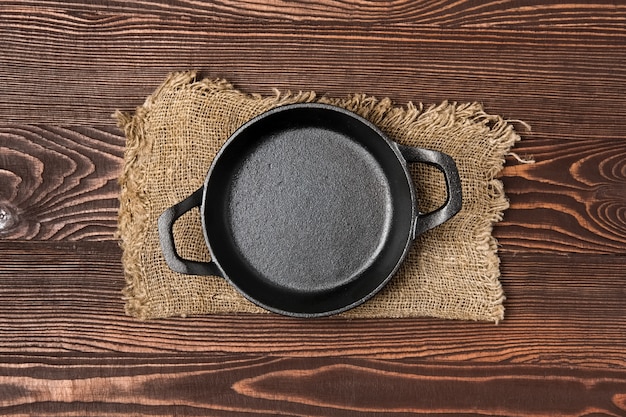 Empty mini cast-iron skillets on wooden table, view from above