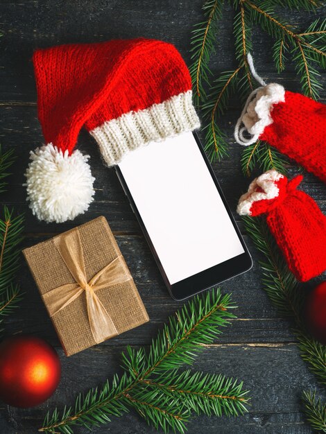 Empty mobile phone with copy space in Christmas hat on dark 