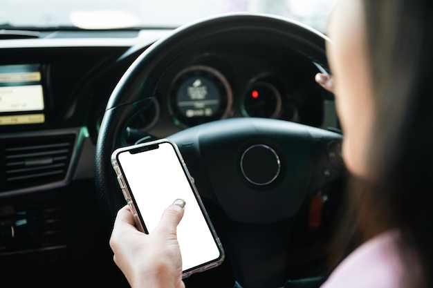 Empty mockup smartphone screen with clipping path. asian young
businesswoman using a smartphone while driving a car, careless
woman driver using a phone while driving a car.