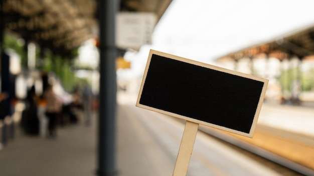 Modello di mockup vuoto etichetta lavagna su sfondo sfocato stazione ferroviaria con locomotiva pubblicità concetto di trasporto ecologico modi di trasporto ecologici copia spazio per il testo