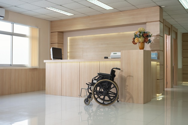 Пустая современная деревянная стойка регистрации с монитором и службой инвалидных колясок в больнице