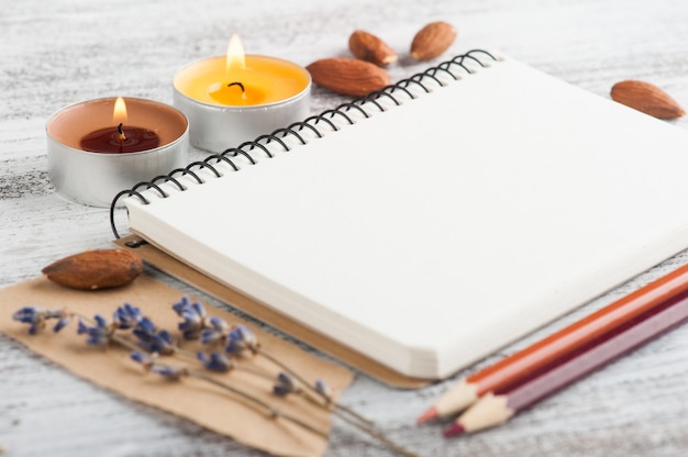 Empty notebook and pencils, lit candles