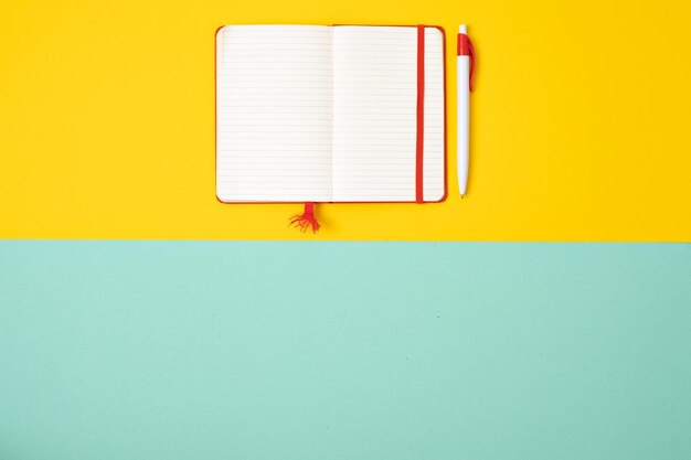 Empty notebook with pen on colored paper background top view Desktop manager