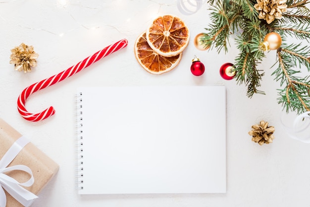 Empty Notebook with wish list and christmas festive decorations on white background.