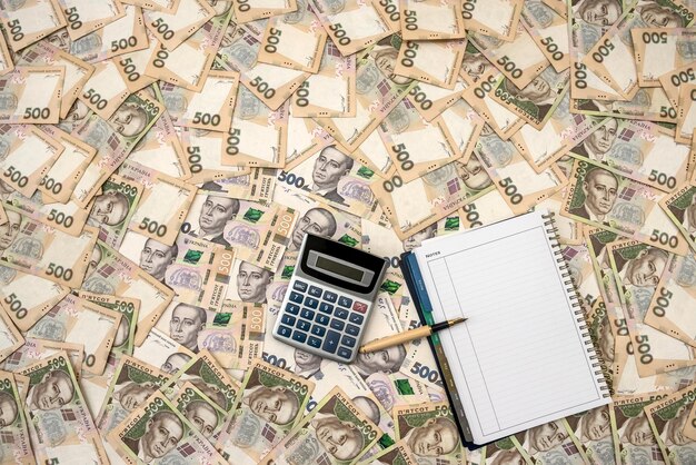 Blocco note vuoto con calcolatrice su sfondi di denaro ucraino. 500 banconote. grivna (uah). vista dall'alto.