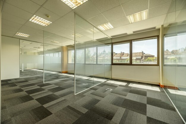 Empty offices with several glass partitions separating cubicles long windows