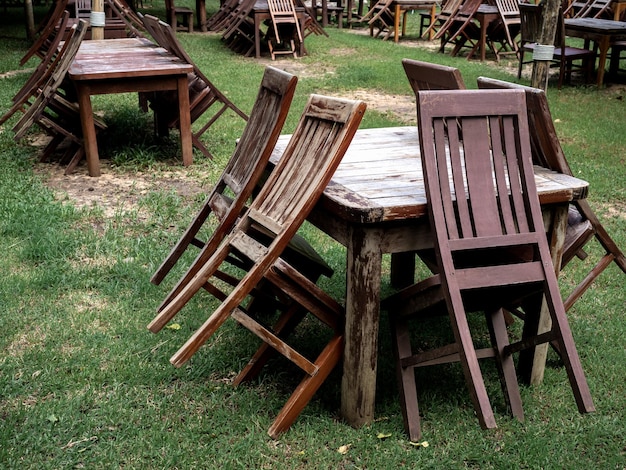 Empty old abandoned wooden dining table set on the green yard garden Outdoor restaurant permanently closed with old dining table no use