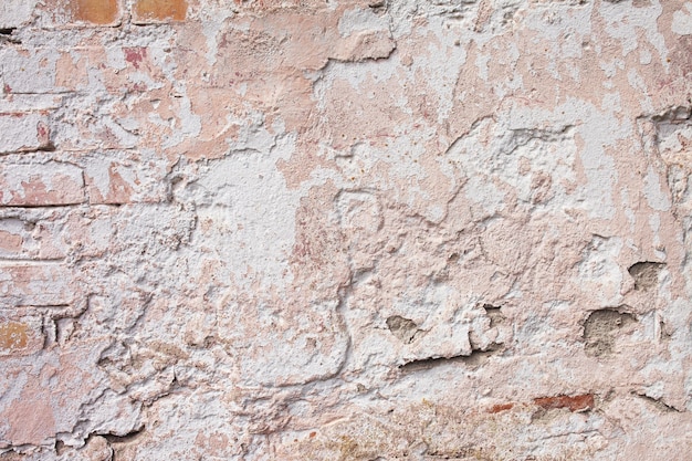 Empty old brick wall texture. Painted grungy wall surface.  Grunge red stonewall background. Shabby building facade with damaged plaster.