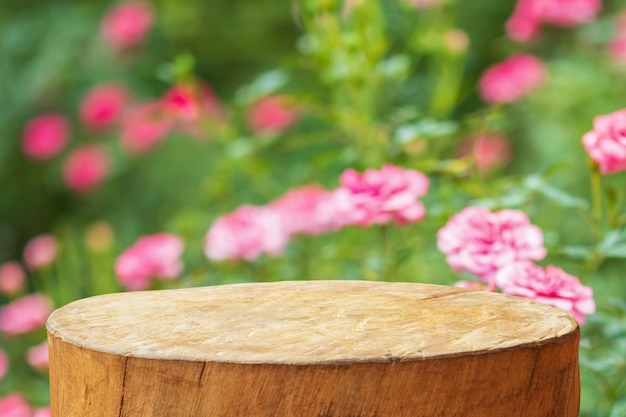 Photo empty old tree stump table top with blur rose garden background for product display