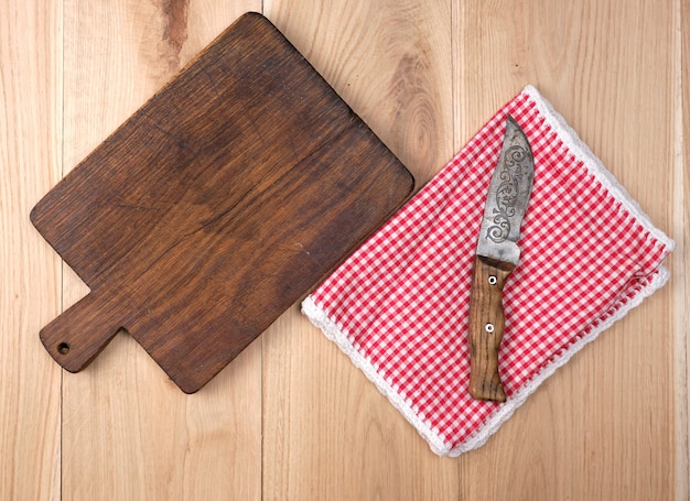 Empty old wooden kitchen cutting board and knife on table