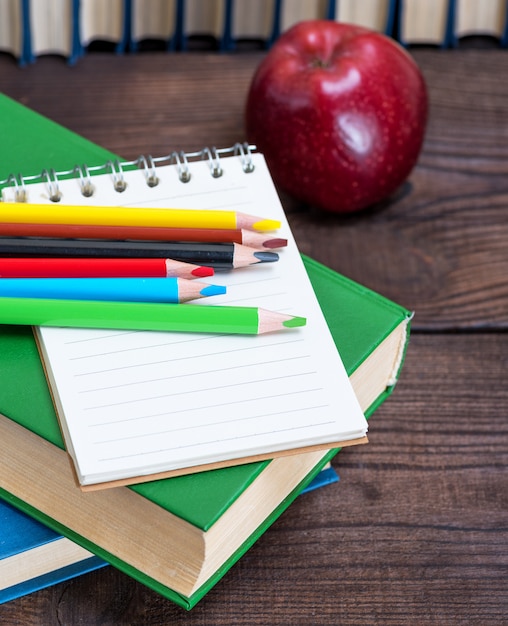  empty open notebook and multicolored wooden pencils