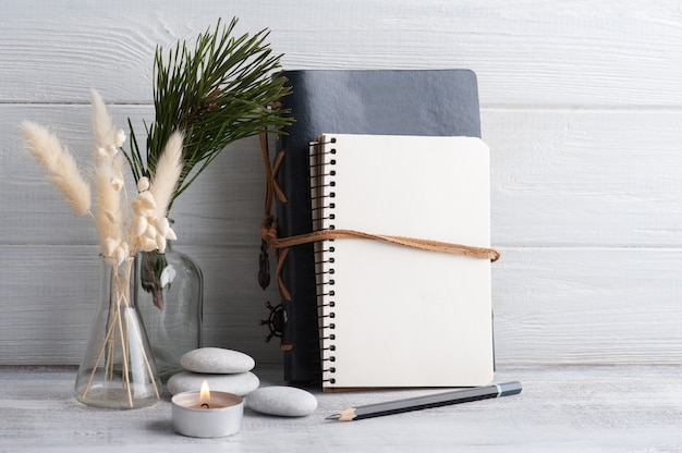 Empty open notebook, pine tree and dry flowers on rustic background. 