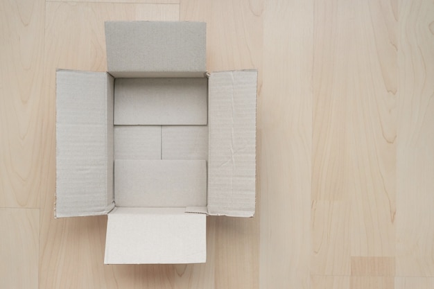 Empty open rectangular cardboard box on wood.