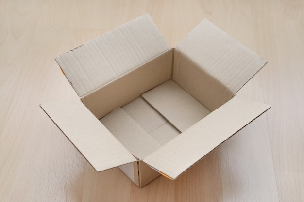 Empty open rectangular cardboard box on wood.
