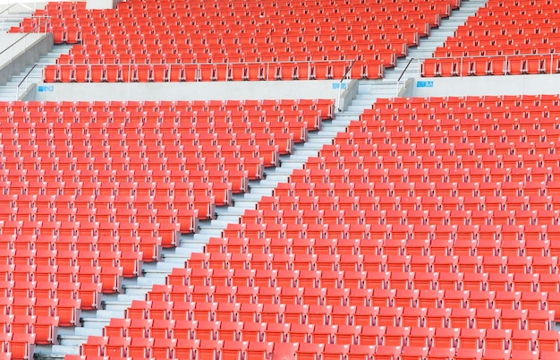 サッカー スタジアムの座席のスタジアム行通路で空のオレンジ色の座席