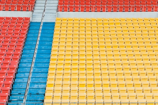 スタジアムの空のオレンジと黄色の座席サッカースタジアムの座席の列