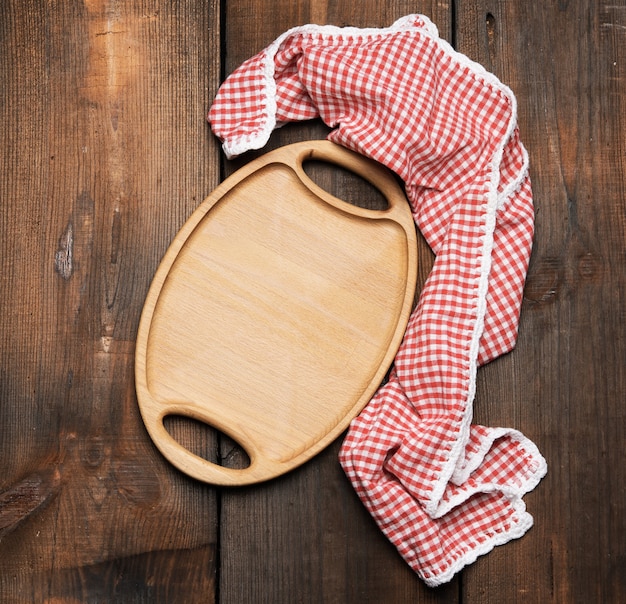 Empty oval brown wooden tray board on a wooden background, top view