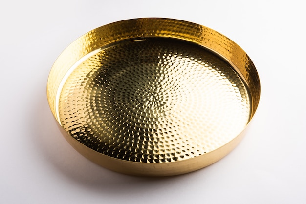 Empty oval or round shape thali or plate made up of brass, pital or gold over white surface