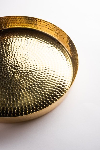 Empty oval or round shape thali or plate made up of brass, pital or gold over white surface