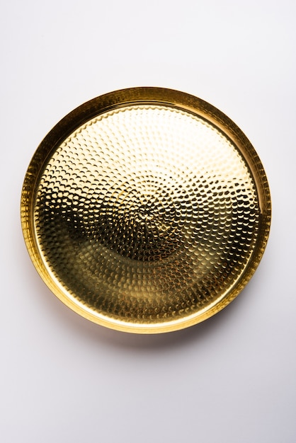 Empty oval or round shape thali or plate made up of brass, pital or gold over white surface