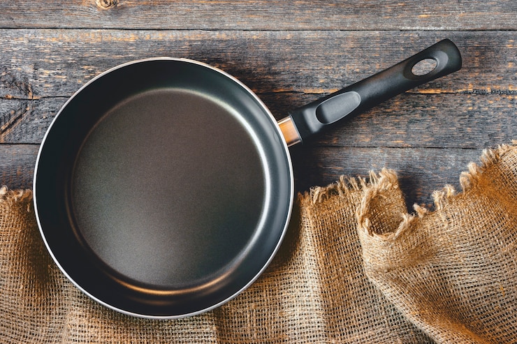 Photo an empty pan on a wooden table and tablecloth